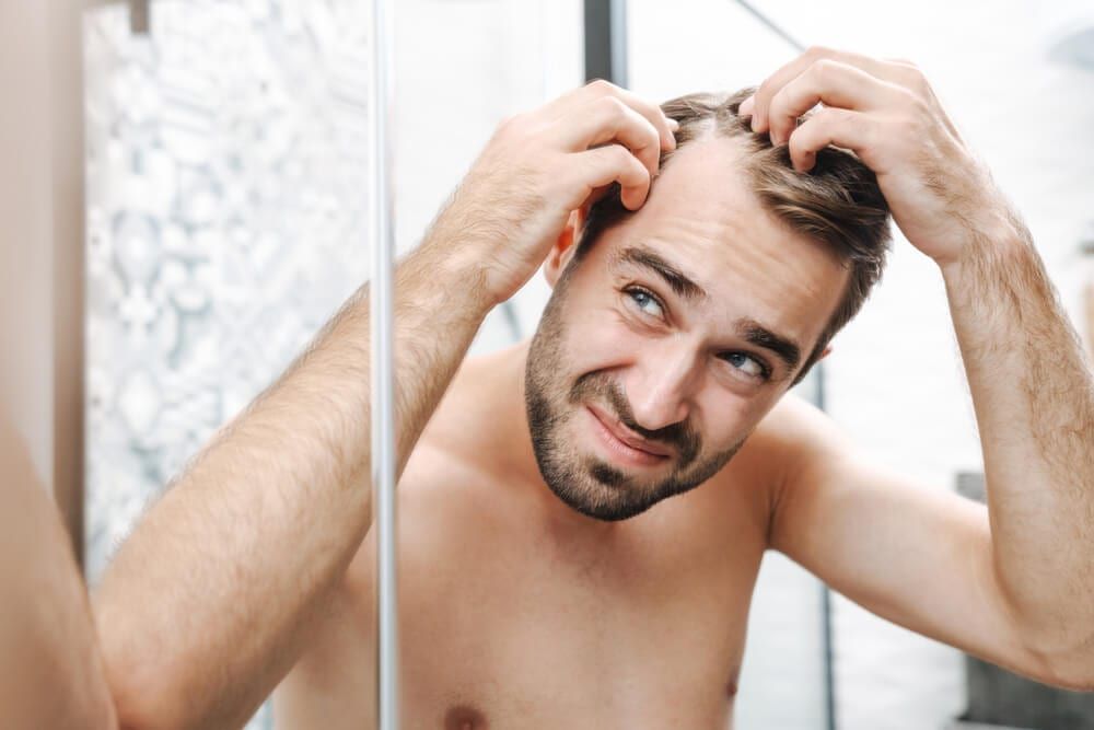 male examining receding hairline